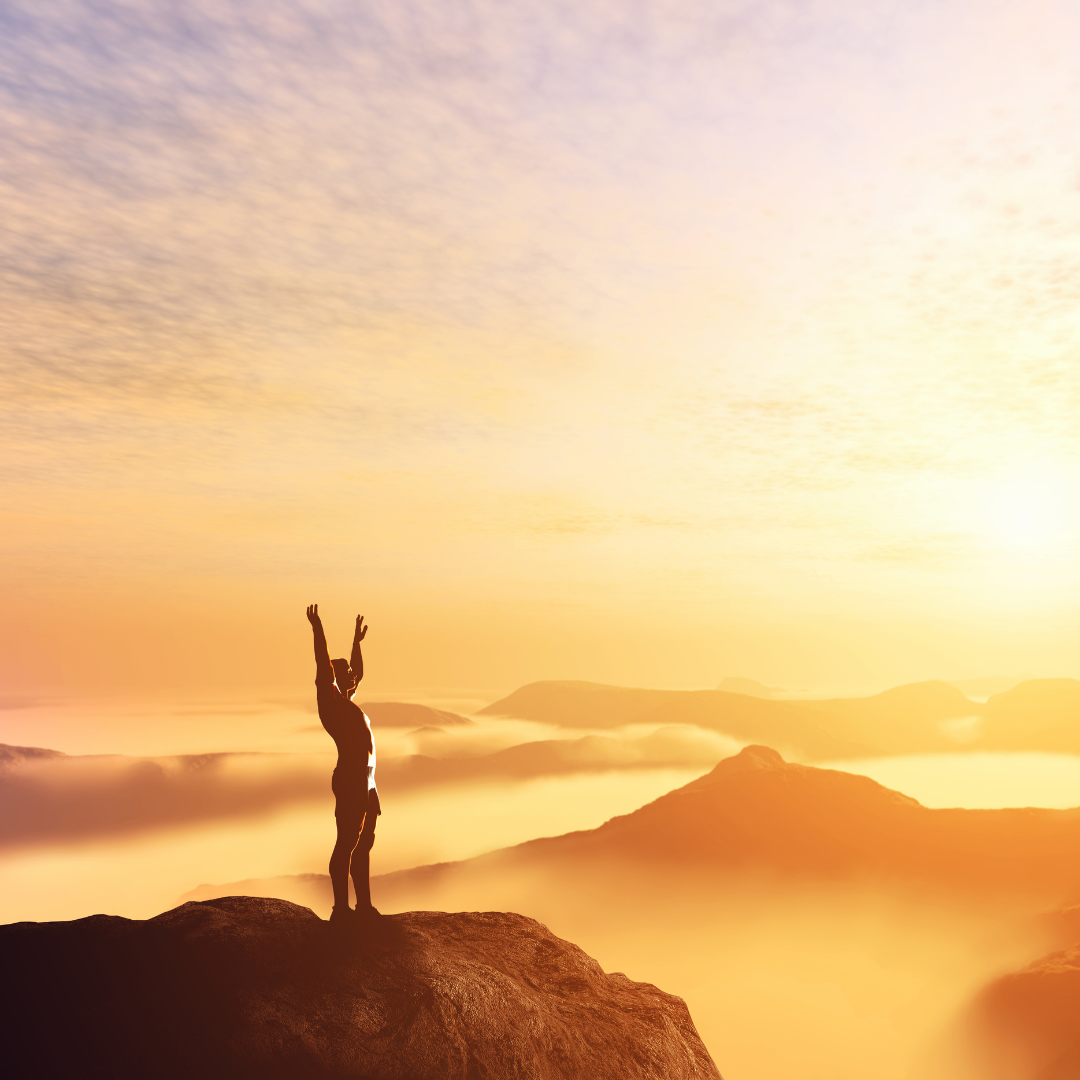 Person standing on a mountain streching their arms up